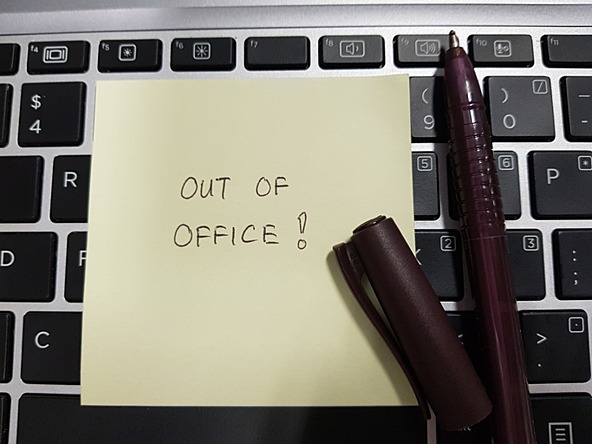 An out-of-office note on desk representing annual leave 